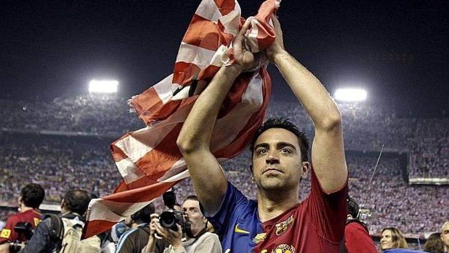 Xavi, ataviado de una bandera del Athletic, aplaude a los aficionados rojiblancos tras la final de Copa celebrada en Mestalla en 2009.