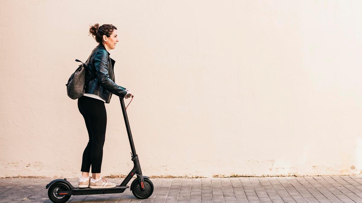 Una mujer circula con un patinete eléctrico. Una mujer circula con un patinete eléctrico.