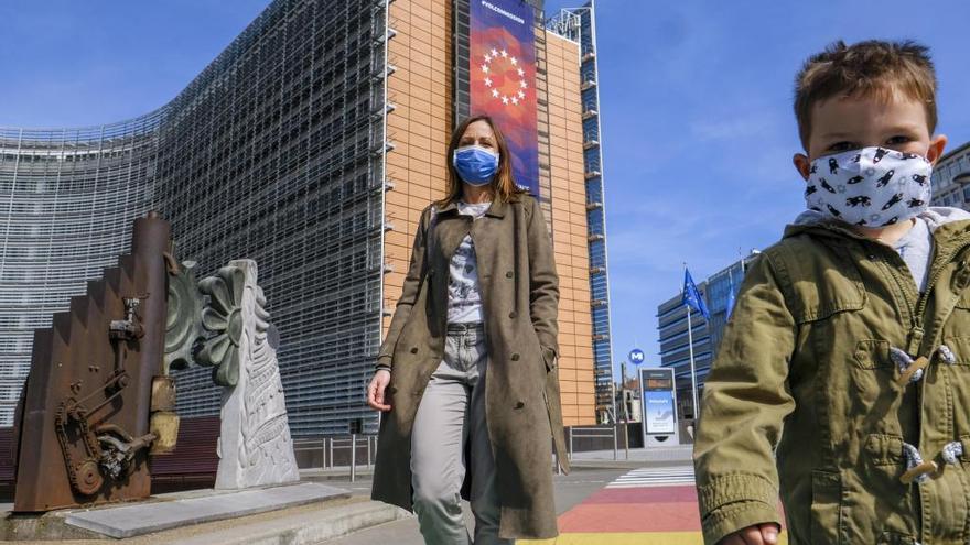 Una mujer y un niño, con mascarilla frente a la sede de la Comisión Europea en Bruselas.