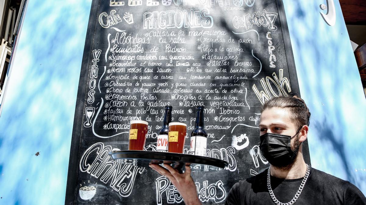 Un camarero lleva cervezas artesanales en una terraza