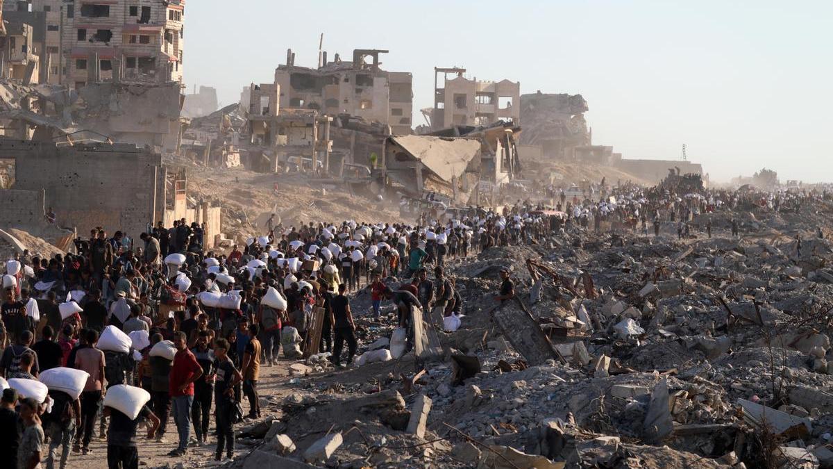 Un numeroso grupo de palestinos traslada sacos de harina conseguidos en una punto de distribución de Ciudad de Gaza.